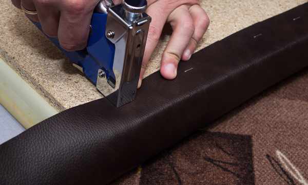 A close-up of a person applying staples to a seat frame